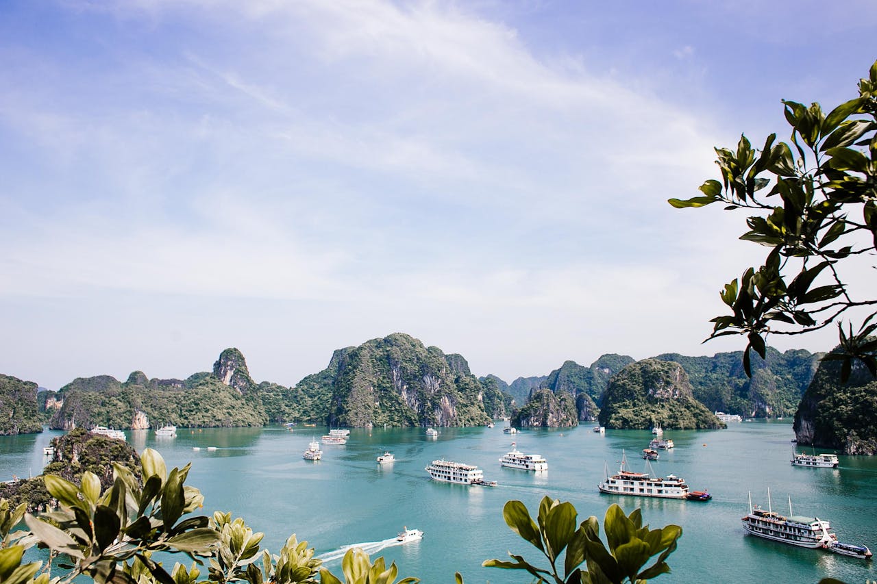 our-services-01 Serene Halong Bay vista featuring iconic limestone islands and boats under a clear sky.
