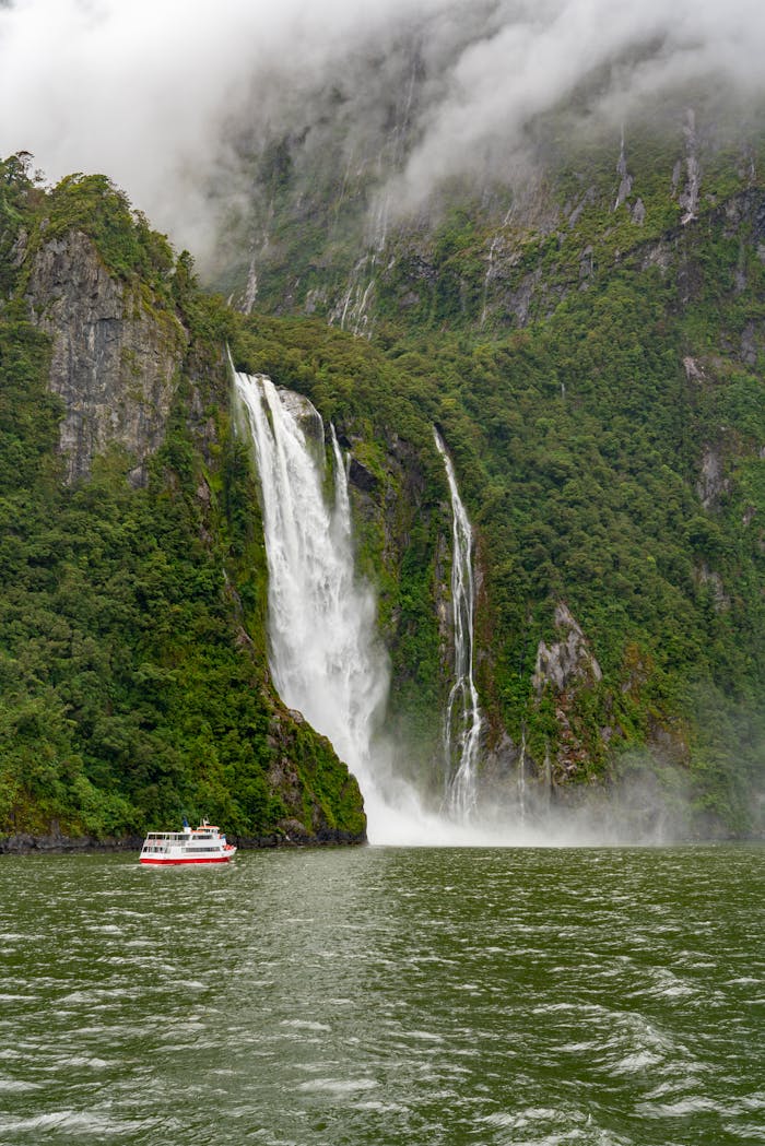 why-choose-us-img Tour boat approaches stunning waterfall in a mist-covered fjord, capturing natures grandeur and serene beauty.
